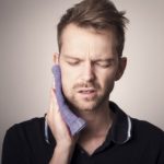 Man in pain holding his cheek with hand, suffering from bad tooth ache