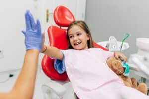 Child high fives a hygienist after a successful dental cleaning and fluoride treatment.